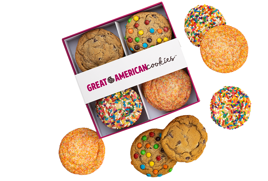 Picture of Assorted Cookies in a box and also scattered around including Original Chocolate Chip, M&Ms , Sugar, and Birthday Cake Cookies